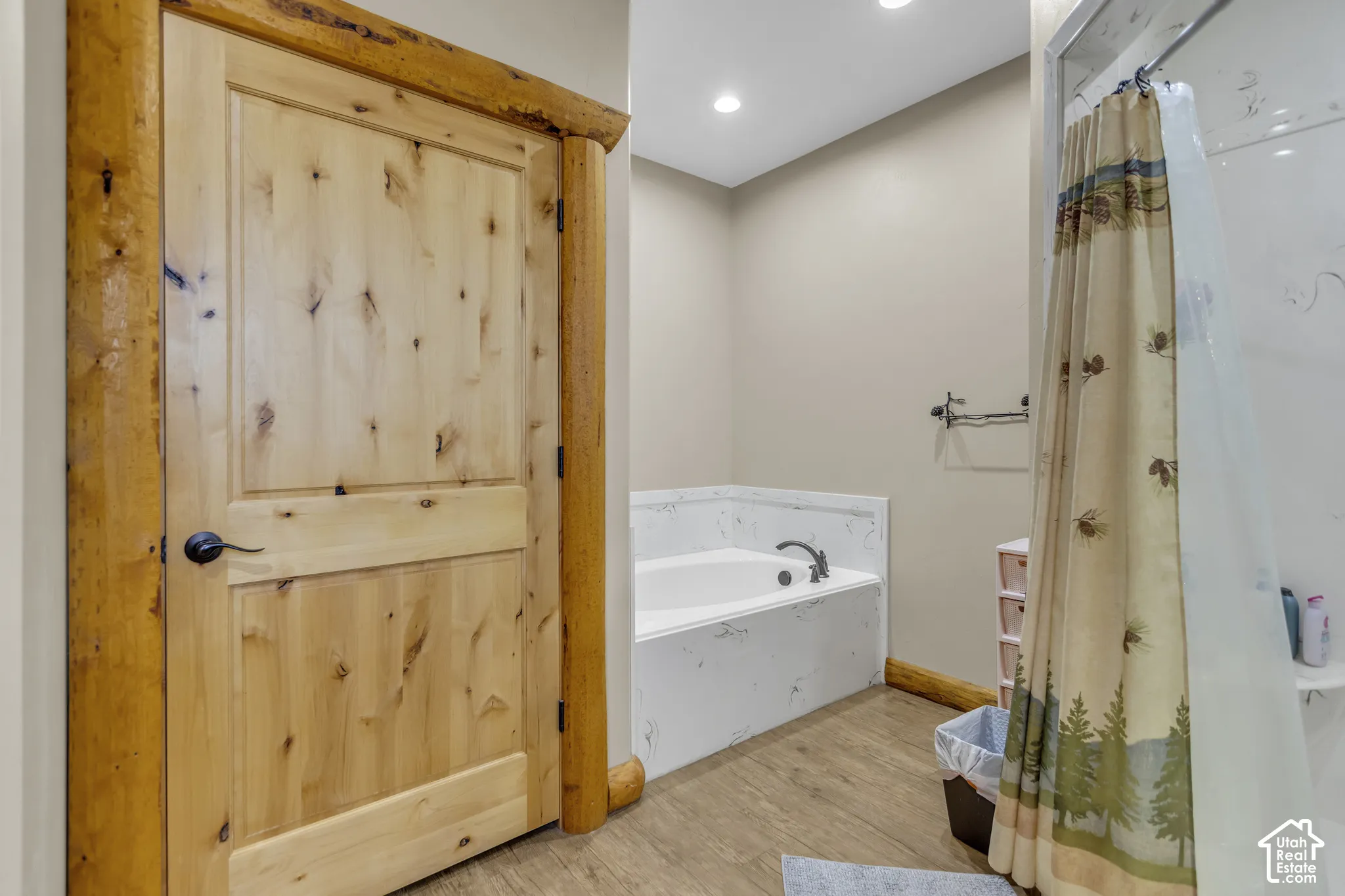 Wood-finish flooring, built-in soaking tub, and a shower with a sliding glass door