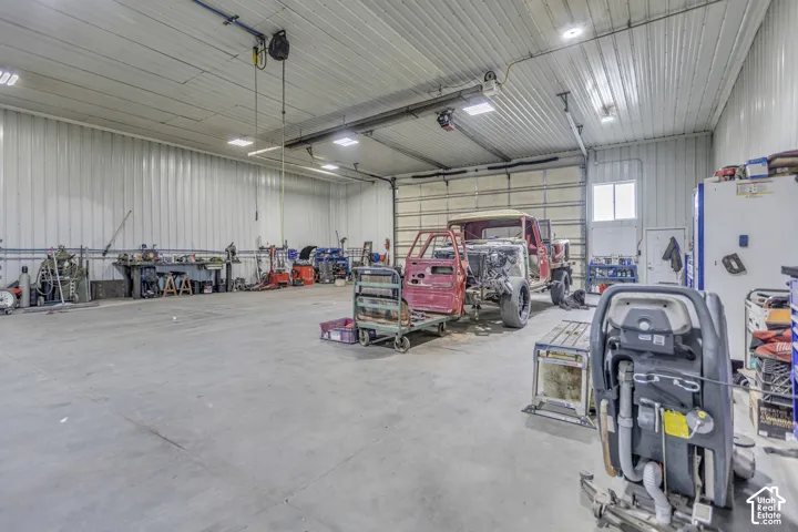 Spacious workshop featuring a concrete floor, corrugated metal walls, and overhead lighting