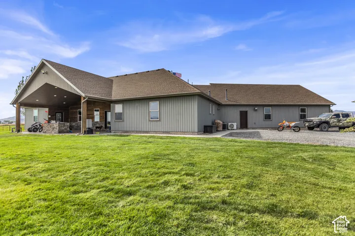 Expansive green lawn with a covered patio featuring a stone-clad outdoor kitchen
