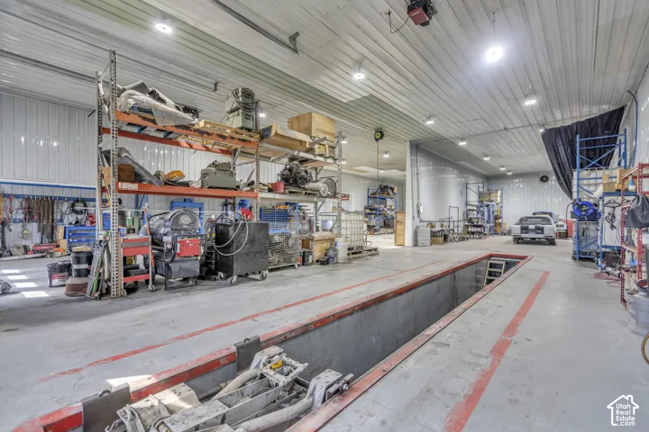 Concrete flooring with an integrated service pit, bright overhead lighting, and abundant storage shelving