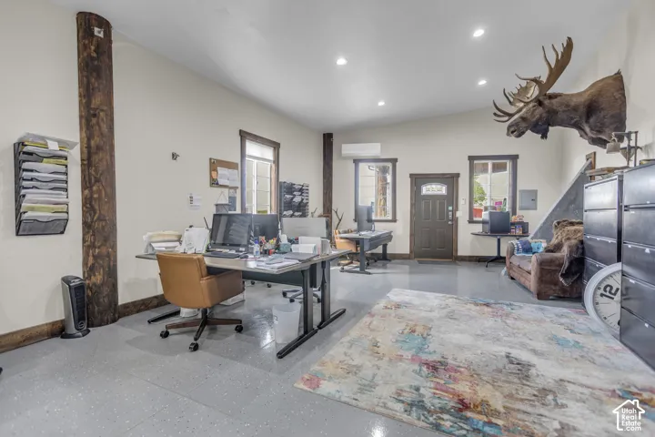 High ceilings with recessed lighting, exposed structural wood columns, wood-trimmed windows, a wood-paneled entry door, and polished concrete flooring
