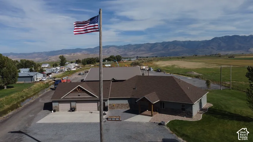 Gabled roofline, attached two-car garage, stone and siding exterior, covered entry, and expansive mountain backdrop
