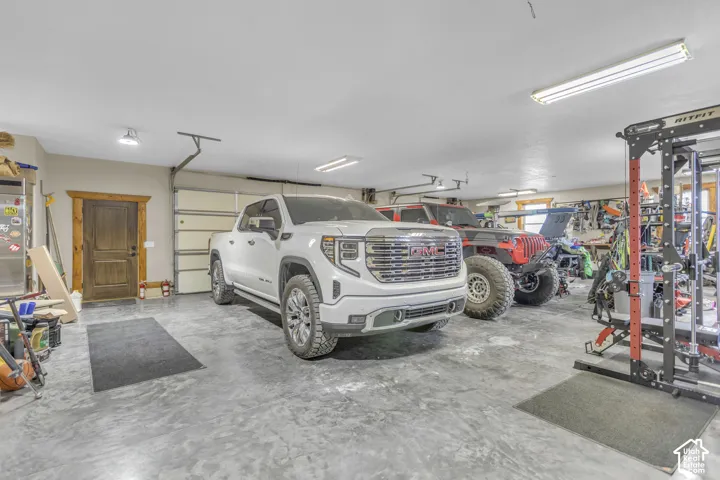 Spacious garage with textured concrete flooring, multiple overhead fluorescent light fixtures, and a wood-paneled overhead garage door