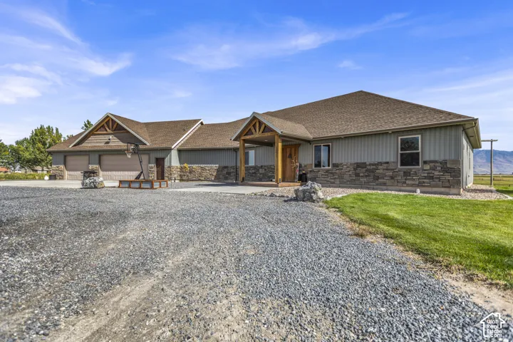 Exterior featuring a stone and siding facade, gable roof, covered entry, and attached garage
