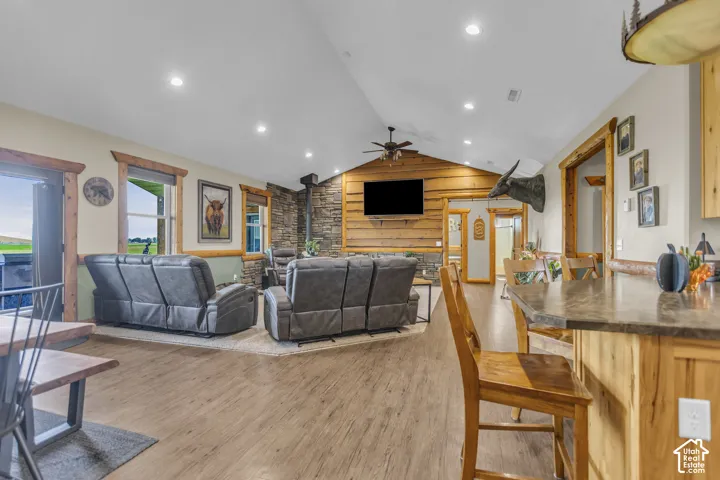 Vaulted ceiling, recessed lighting, wood-finish flooring, stone-clad fireplace, and natural wood trim accents