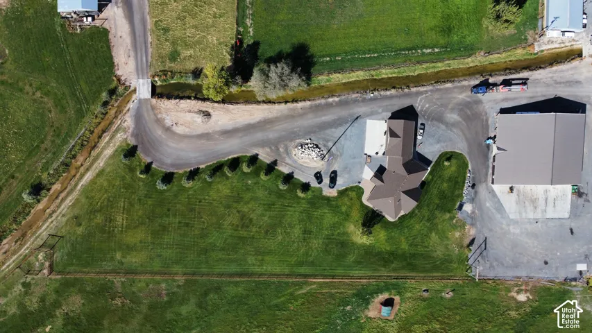 Expansive green lawn areas, gravel driveways, and a multi-level roofline on the primary structure