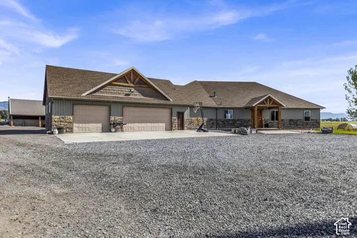 Ranch-style residence featuring a two-car garage, stone veneer accents, and a covered entry porch