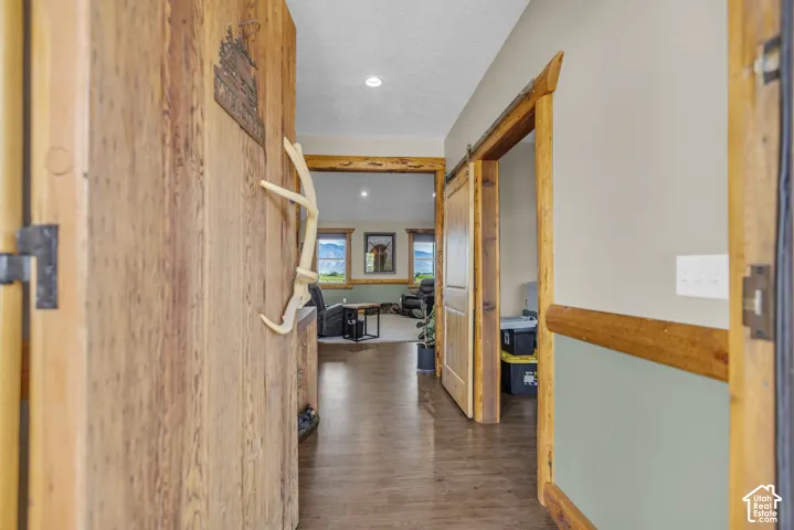 Wood-panel wall with built-in decorative element, wood-finish flooring, recessed lighting, and wood-framed barn door
