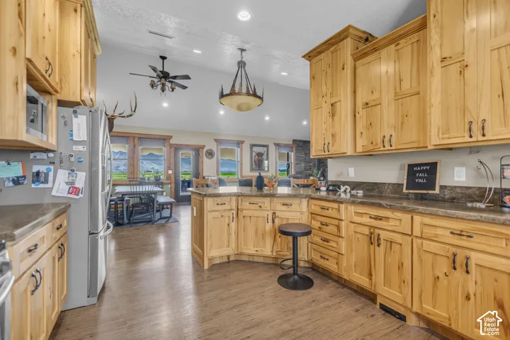 Kitchen featuring wood cabinetry, dark countertops, a central island, and wood-finish flooring