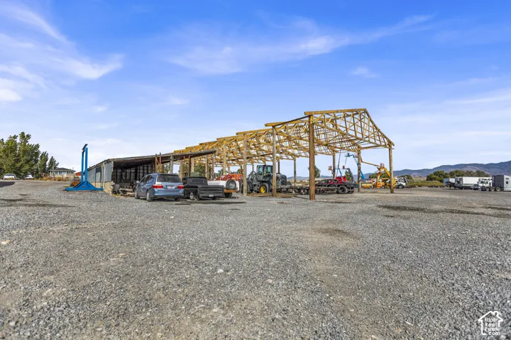 Open-air wood-framed structure, gravel surfacing, and metal-sided outbuilding