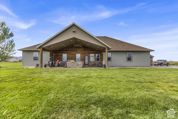 Expansive rear exterior featuring a covered patio, stone veneer accents, wood siding, and metal siding
