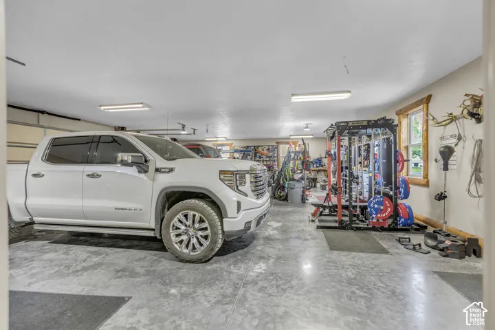 Spacious garage with durable concrete flooring, multiple overhead lighting fixtures, and a window with wood trim