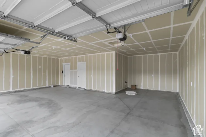 Concrete flooring, two panel doors, and overhead garage door system