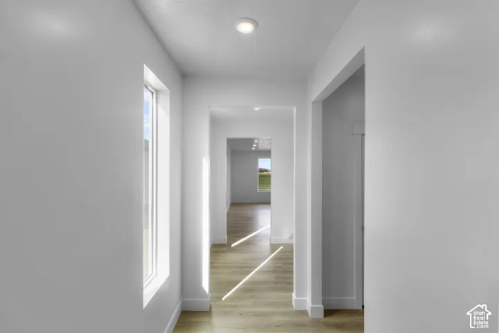 Recessed ceiling lighting, wood-finish flooring, white trim, and a window providing natural light