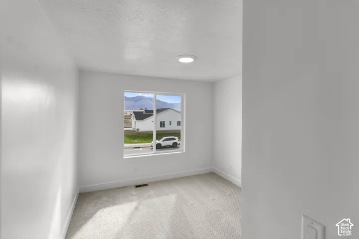Recessed ceiling lighting, neutral carpet flooring, white painted walls, and a large window