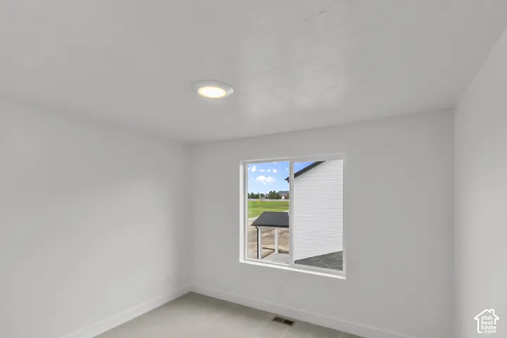 Recessed ceiling light with a white trim, single pane window, light-toned carpeting, and light wall finishes