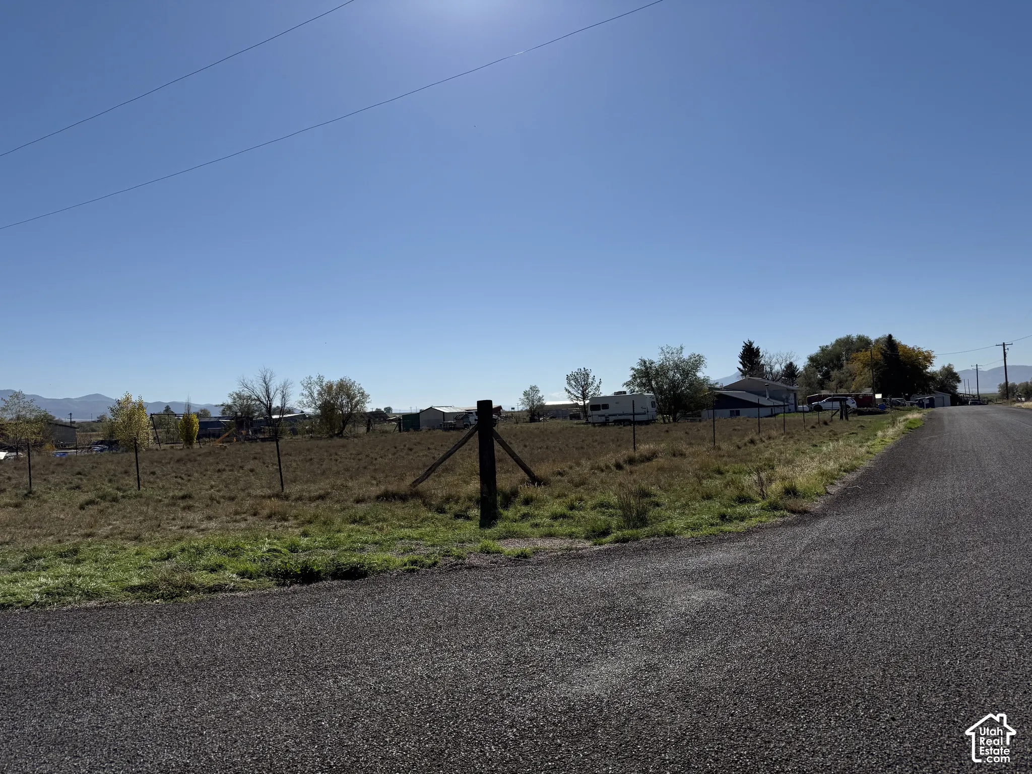 Expansive open lot with a wire fence and a gravel road