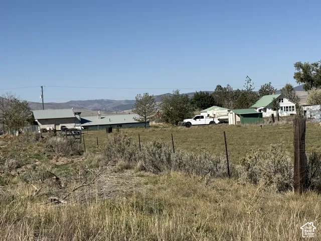 Expansive rural property featuring a large open field, distant mountain scenery, and multiple structures