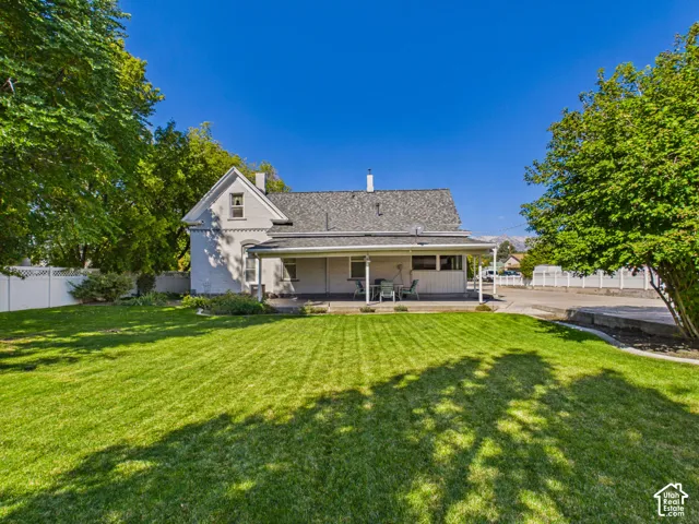 Expansive lawn with mature trees, white privacy fencing, and a covered porch