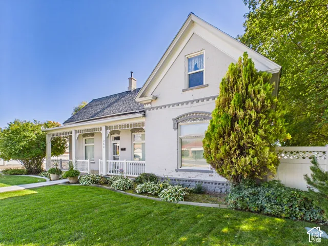 Gabled roofline, front porch with balustrade, arched window lintels, mature landscaping, and a manicured lawn