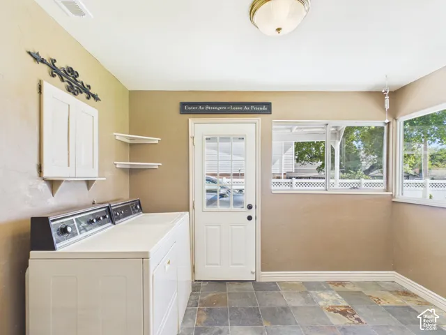 Stone tile flooring, white shaker-style wall cabinet, white interior door with glass insert, recessed lighting, and multiple windows