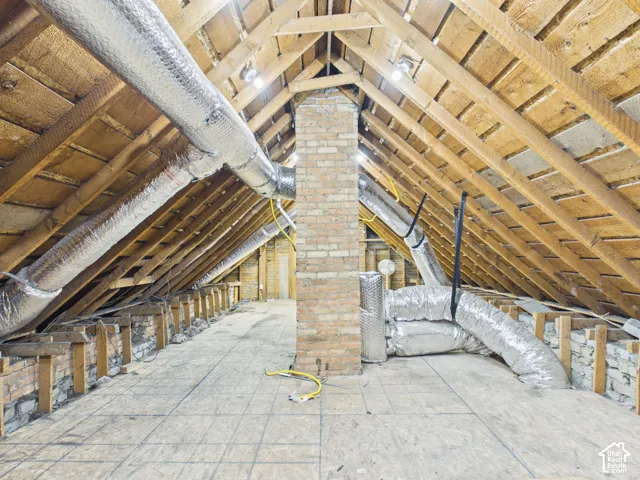 Exposed wood rafters, brick chimney, plywood subfloor, and insulated ductwork
