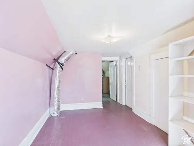 White built-in shelving, painted wood-finish flooring, white trim, and a flush-mount ceiling light