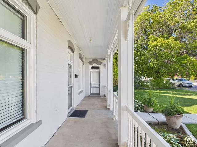 Covered front porch featuring white painted brick, decorative porch columns, and a balustrade railing
