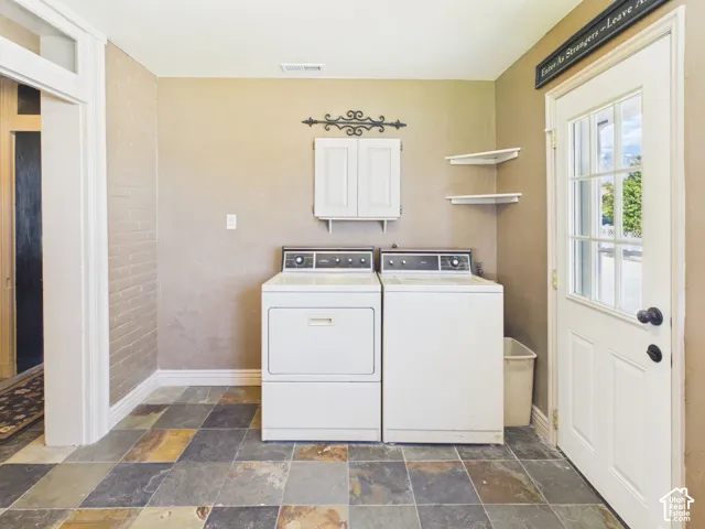 Multicolor slate-style floor tiling, white overhead cabinetry, and corner shelving