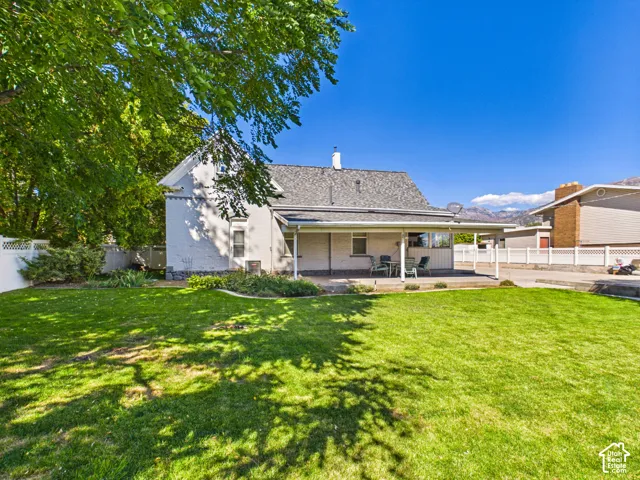 Expansive lawn with established landscaping, white picket fencing, and a covered patio area