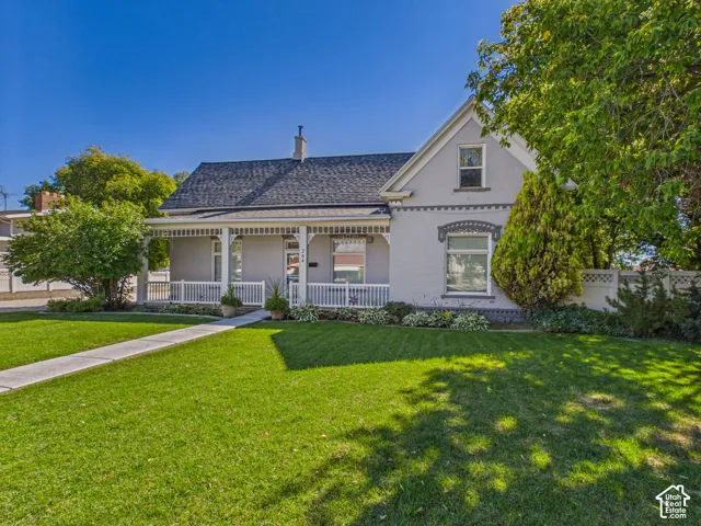 Gable roofline, covered front porch, decorative porch railing, front yard, and mature trees