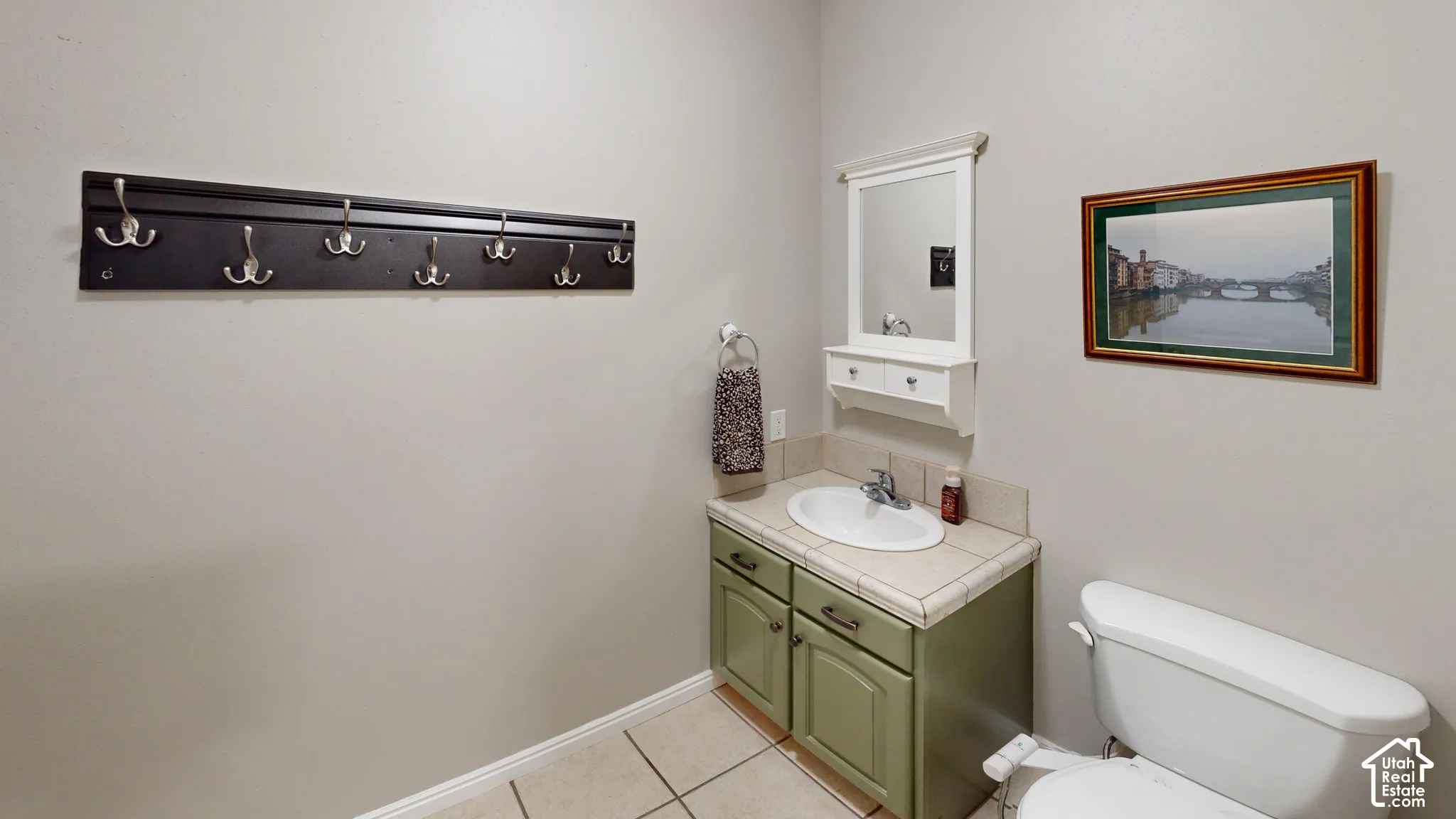 Tile flooring, single basin sink, white toilet, vanity with storage, wall-mounted mirror