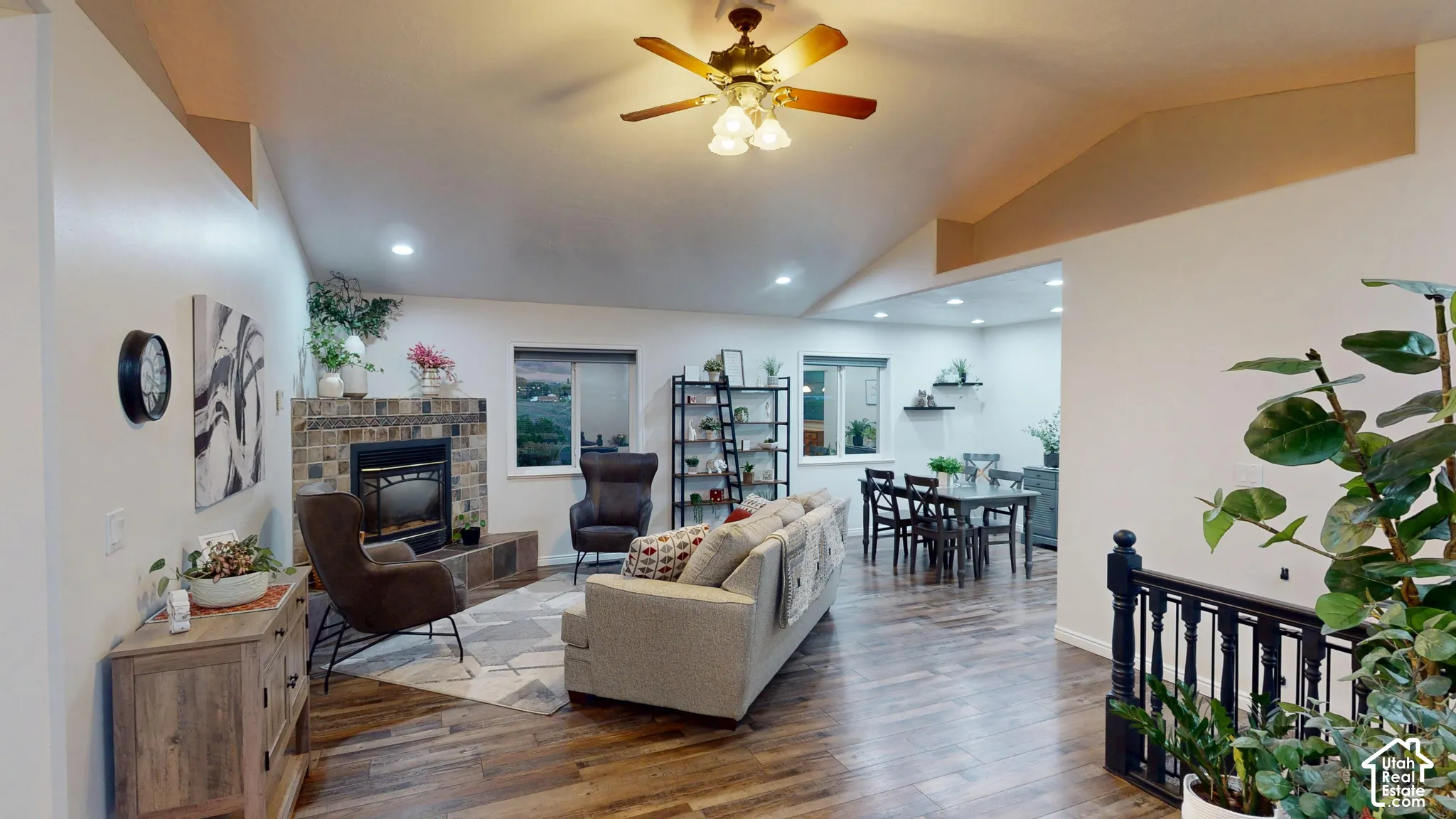 Vaulted ceiling with a ceiling fan, a fireplace with a stone surround, recessed lighting, and wood-finish flooring