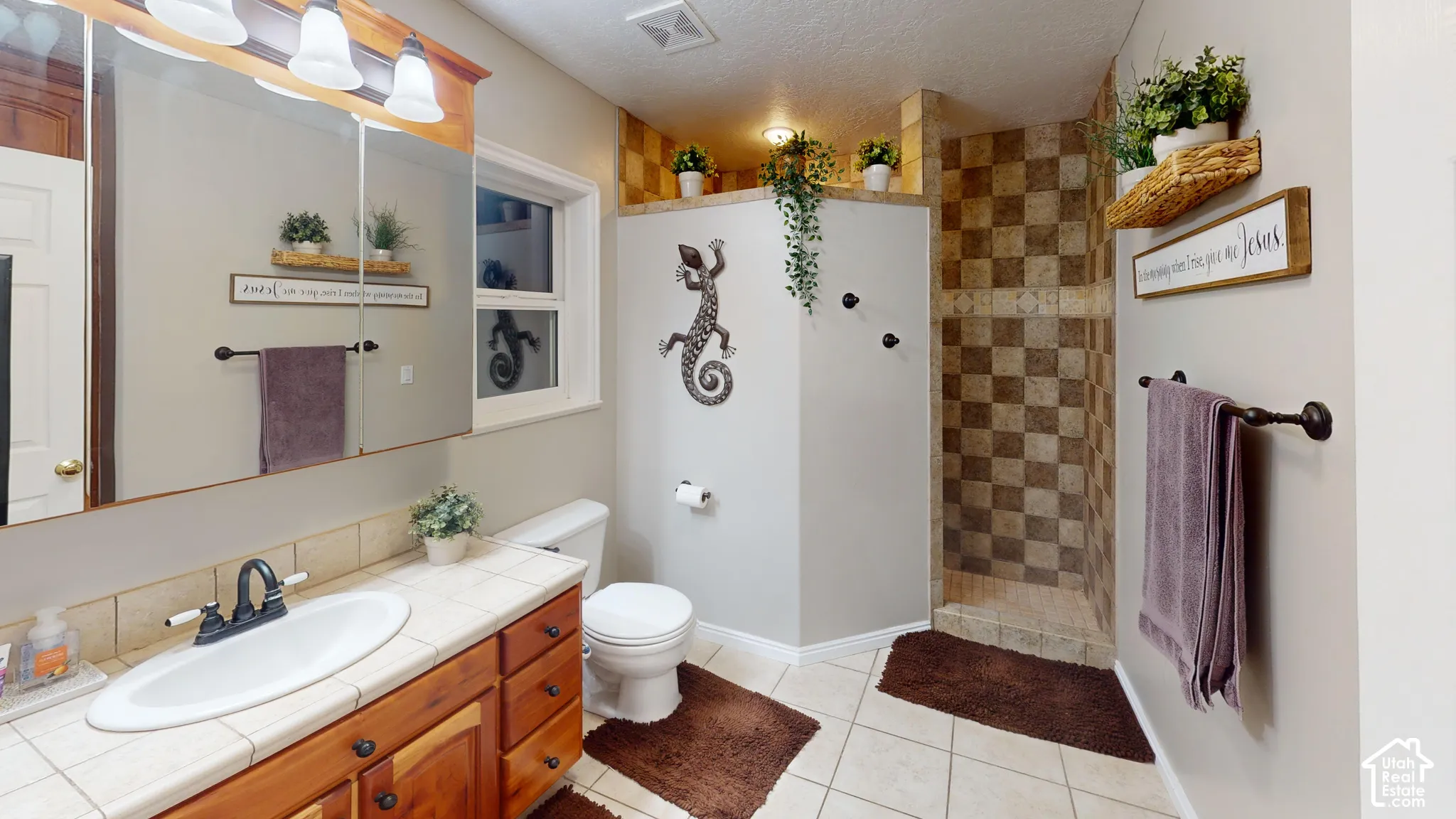 Walk-in shower with checkerboard tile, wood-finish vanity with a tile countertop, integrated sink, and medicine cabinet with overhead lighting