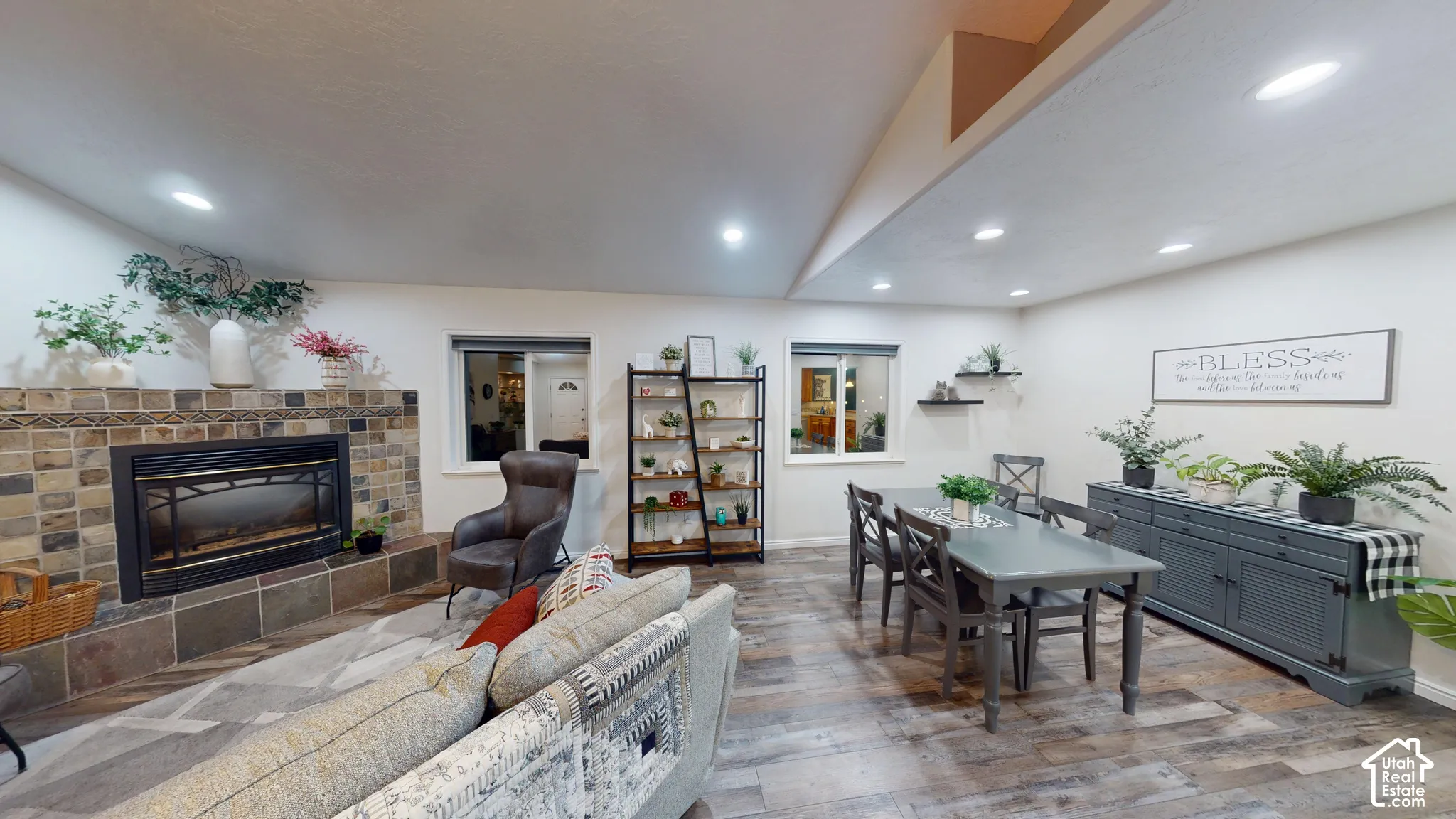 Stone-clad fireplace with mantel, recessed lighting, wood-finish flooring, and a built-in shelving unit
