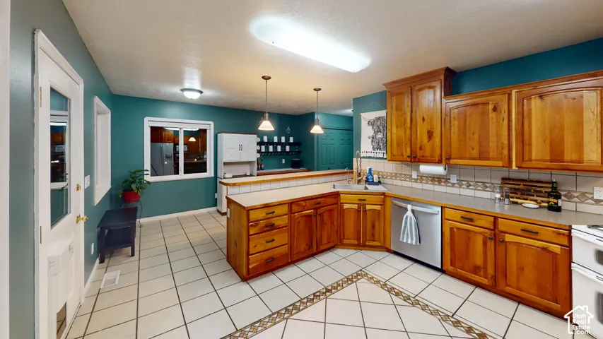 Tile flooring with decorative inlay, wood cabinetry, built-in kitchen island, stainless steel dishwasher, and a window