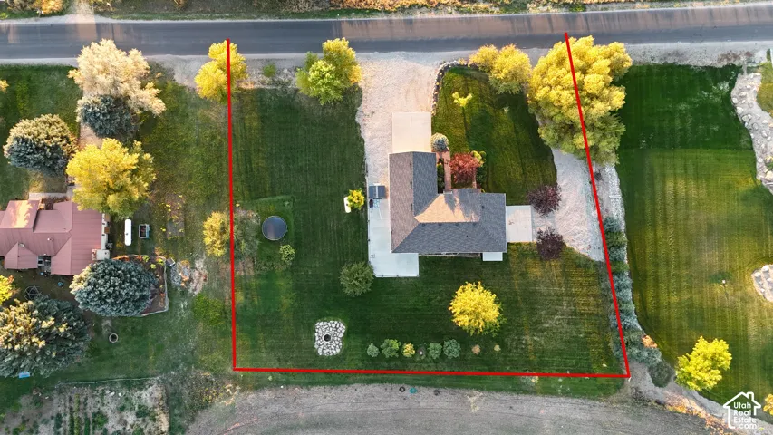 Expansive property featuring a gravel driveway, mature trees, manicured lawns, and a concrete patio