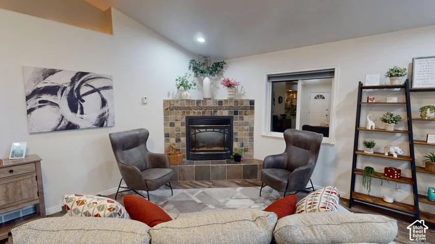 Vaulted ceiling, tiled fireplace with hearth, recessed lighting, and a large window