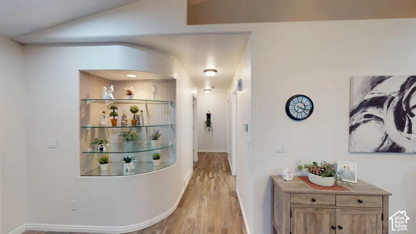 Hallway featuring wood-finish flooring, recessed lighting, and a built-in display niche with glass shelving