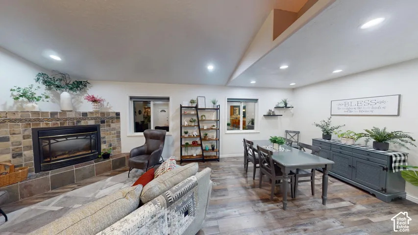 Stone-clad fireplace with mantel, recessed lighting, wood-finish flooring, and a built-in shelving unit