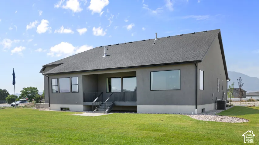 Stucco exterior with a dark shingle roof and a concrete patio