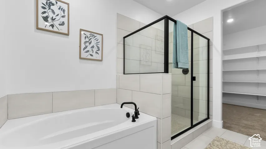 Built-in soaking tub with matte black fixtures, glass-enclosed shower with matte black framing, and a tiled shower surround
