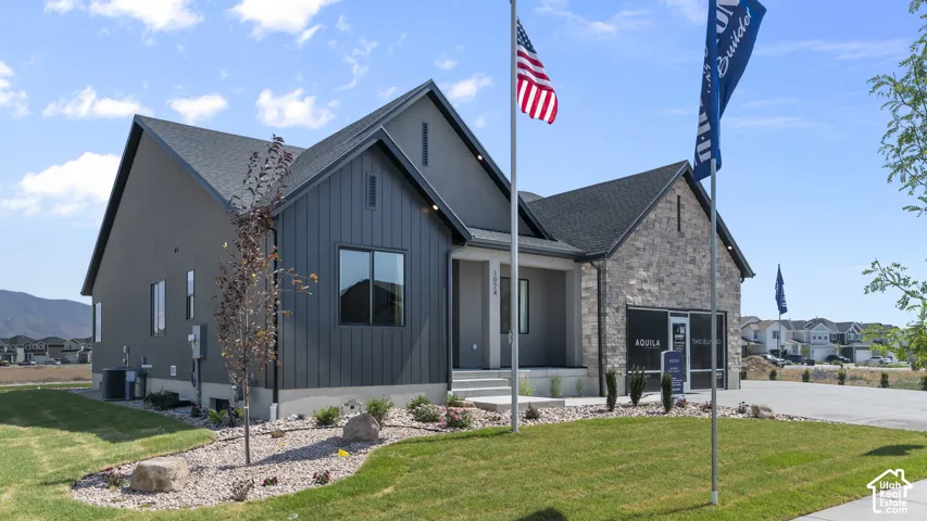 Contemporary exterior featuring vertical board siding, stone accents, a covered entry, and a prominent garage