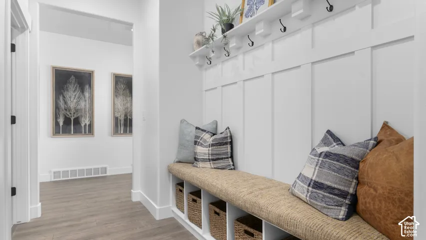 Built-in bench with storage cubbies, wall-mounted coat rack with shelf, and wood-finish flooring