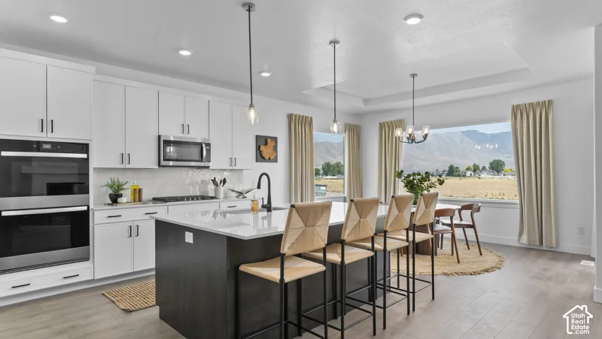 White shaker cabinetry, stainless steel appliances, and a kitchen island with seating