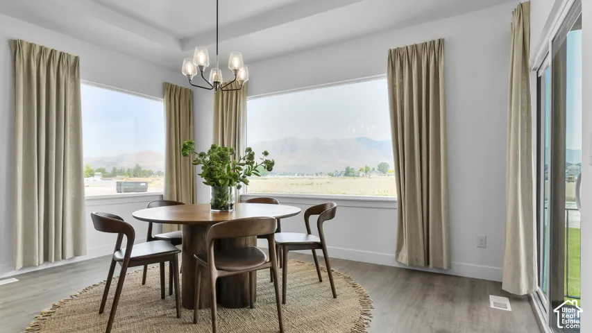 Tray ceiling with a contemporary chandelier, multiple large windows, wood-finish flooring, and sliding glass doors