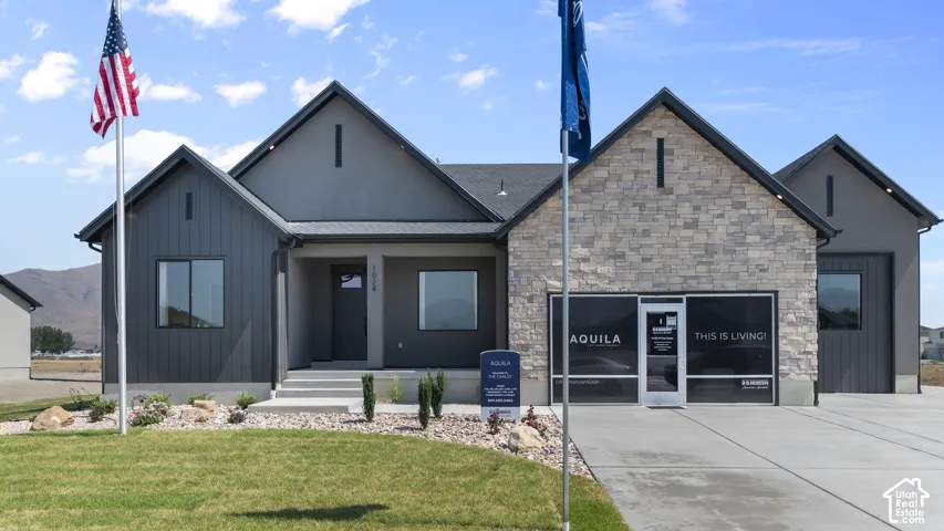 Contemporary exterior featuring a stone facade, dark vertical siding, a covered entry, and a two-car garage
