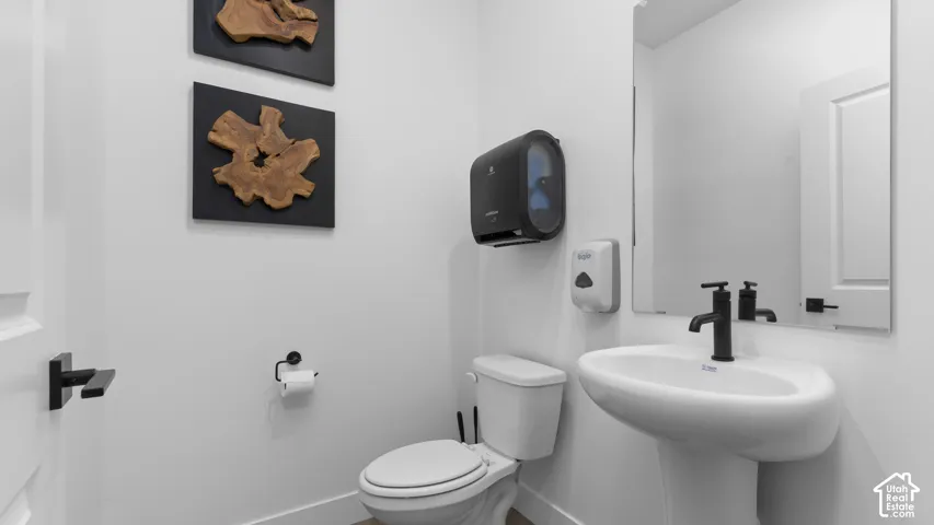 Pedestal sink with a matte black faucet, wall-mounted rectangular mirror, and white panel door with black hardware