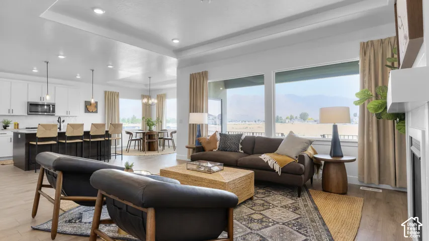 Open-concept living space with wood-finish flooring, recessed lighting, and a modern fireplace