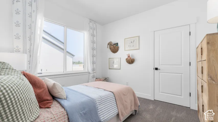 White walls, large window, paneled door with dark hardware, and gray carpeting
